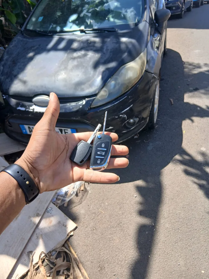 Une clé et une télécommande présentées devant une citadine Ford. — AttoVa Service, Mayotte.