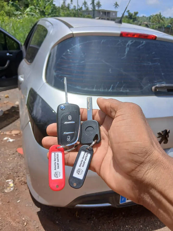 Une clé et une télécommande présentées devant un véhicule Peugeot. — AttoVa Service, Mayotte.