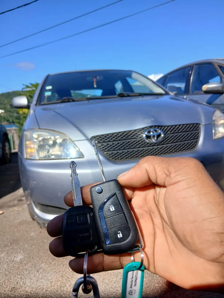 Une clé et une télécommande présentées devant un véhicule Toyota. — AttoVa Service, Mayotte.