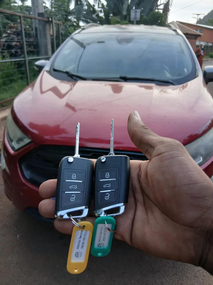 Deux clés à télécommande présentées devant un véhicule Ford rouge. — AttoVa Service, Mayotte.